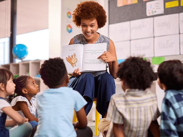 This photo shows a teacher reading an authentic text aloud to a group of students, encouraging the building of background knowledge and vocabulary, discussion and collaboration.