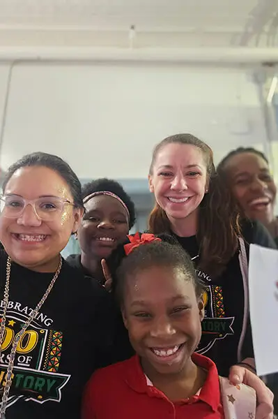 Students and teachers stand together smiling at the Susie King Taylor Community School in Savannah, Georgia.