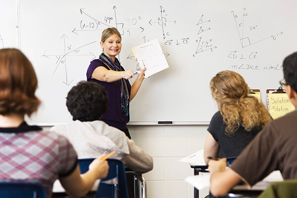 Photo of a teacher teaching math to a classroom of high school students.