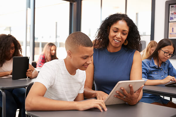 A female Spanish-language teacher using technology in a lesson with  a high school student.