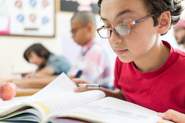 Middle school students intently study texts in front of them at their desks
