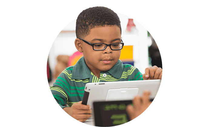 Elementary age boy using a tablet in a classroom.