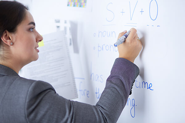 A closeup image of a student writing in a notebook with a pencil.