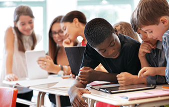 a group of students sitting at a desks using  laptops