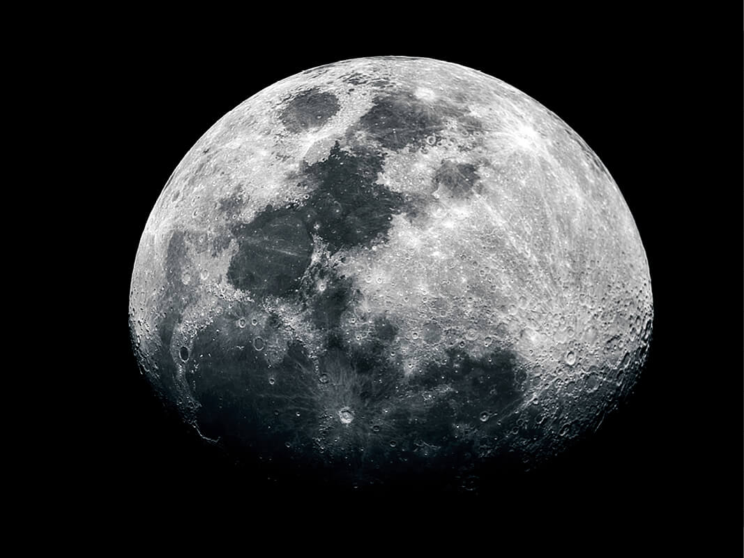 This shows a clear photo of the Earth’s moon, half in shadow, displaying a detailed view of its craters and other textures. The moon is considered a naturally occurring event, or a phenomenon.