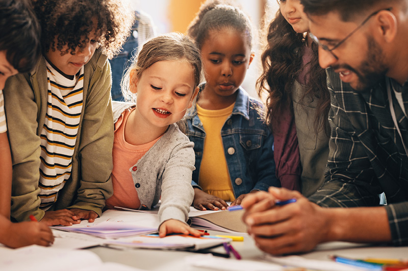 Students and a teacher gathered around a table engaging in a lesson.