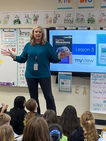  An Elmbrook, WI teacher standing in front of a group of students with a screen in the back that reads myView Lesson 3.