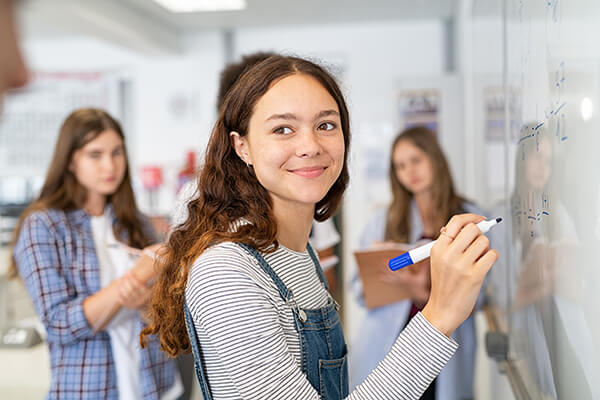 Photo of high school students working together in a classroom on a math problem.