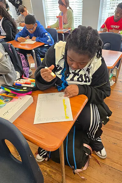 a student from Susie King Taylor Community School working on a literacy lesson at his desk.
