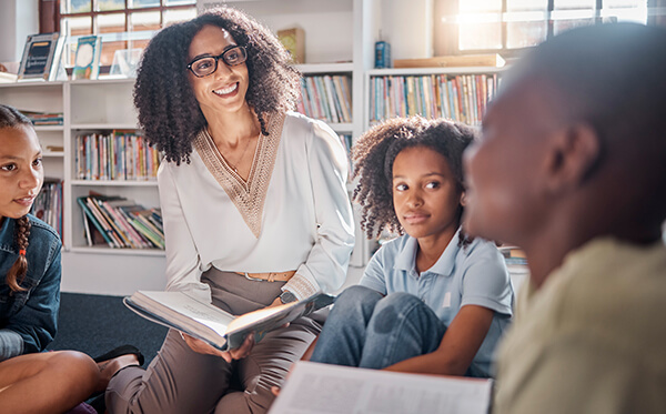 Teacher listening to a young student express her thoughts about a book they are reading together at school.
