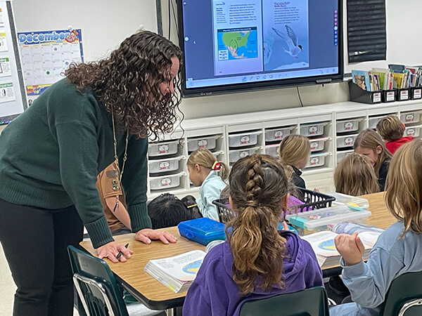 A teacher working with a small group of elementary students on a reading lesson from myView Literacy.