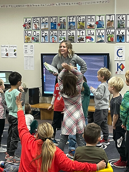  An Elmbrook, WI teacher stands in front of an active group of elementary students with a myView Literacy lesson book in her hand.