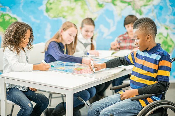 A group of middle school students working together on an inquiry-based geography lesson around a table with a map of the world on it.