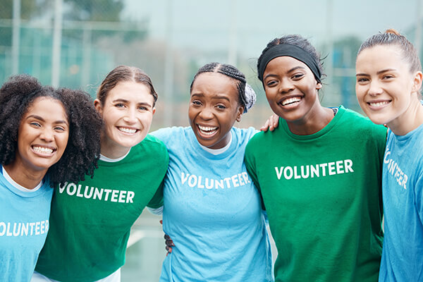 A group of high school students smiling and standing side by side wearing shirts that read “volunteer.”