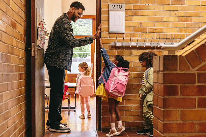 Elementary aged students stand in an organized line waiting to go into the classroom.