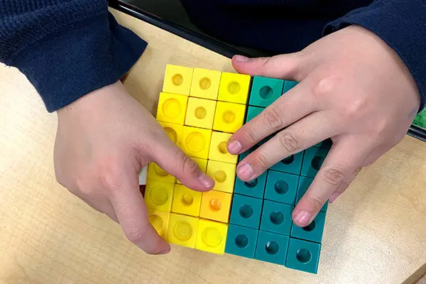 Elementary student decomposing numbers with base-ten blocks to build foundational number sense and numeracy skills.