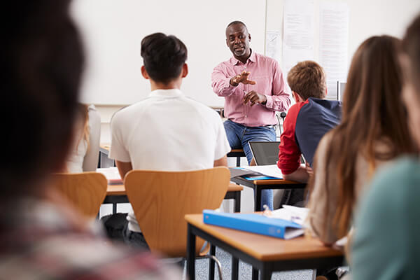 A male Spanish teacher using differentiated instruction strategies in a classroom of high school students with diverse learning needs.