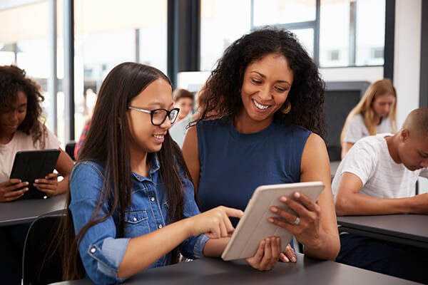 Teacher providing word-reading intervention to a middle school student on a tablet computer.