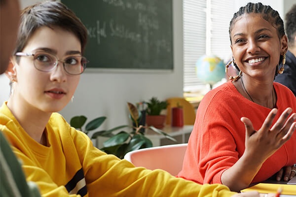 High school aged students talking with partners in a social studies classroom.