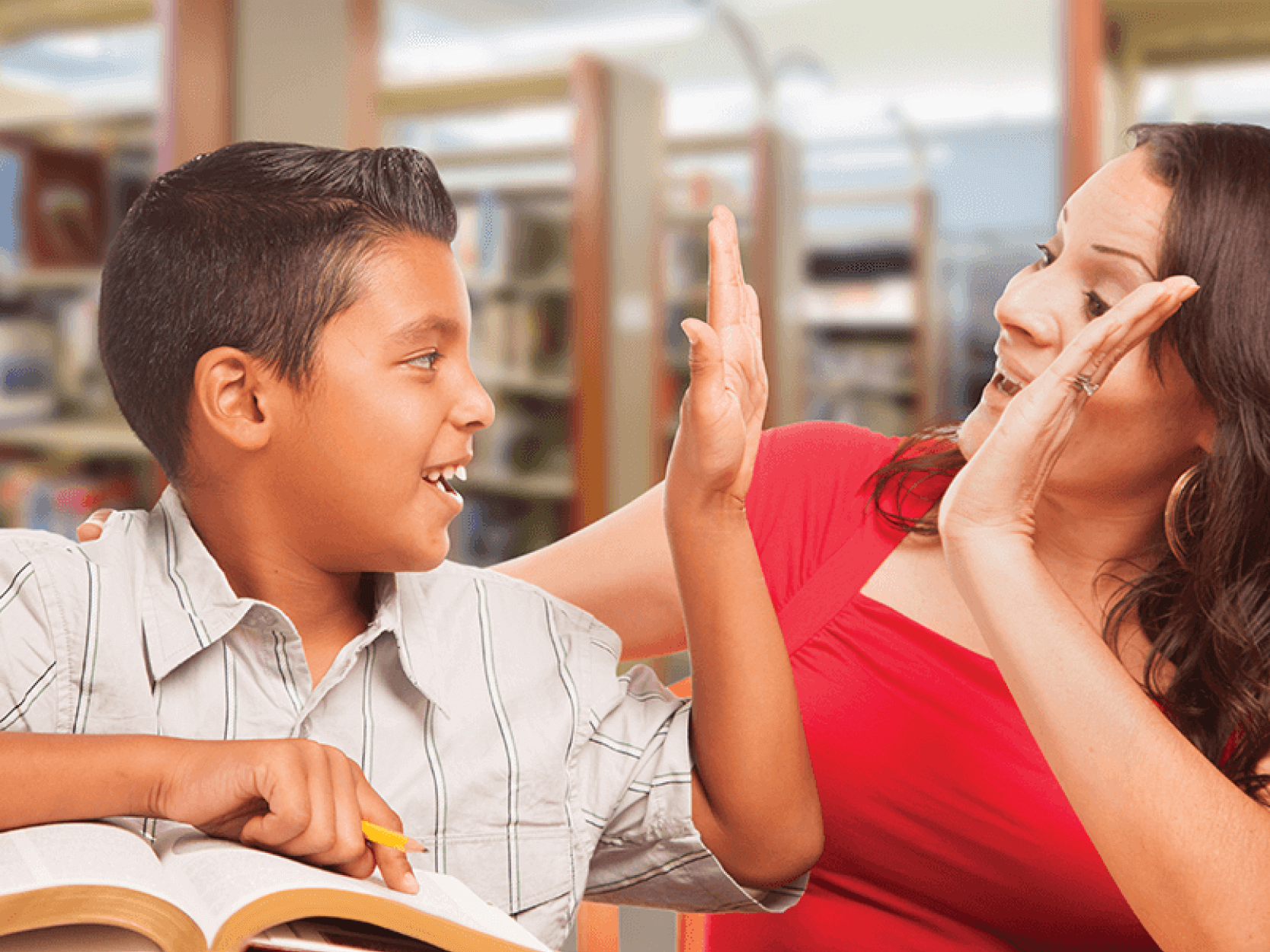 A successful student receiving reading feedback high-fives an adult