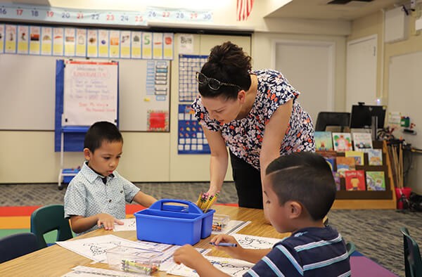A teacher at Elk Grove Unified School District in California working with young students on their math lessons.