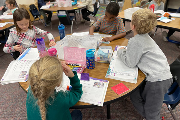 A group of Elmbrook, WI elementary students sit around a round table working on a myView lesson.