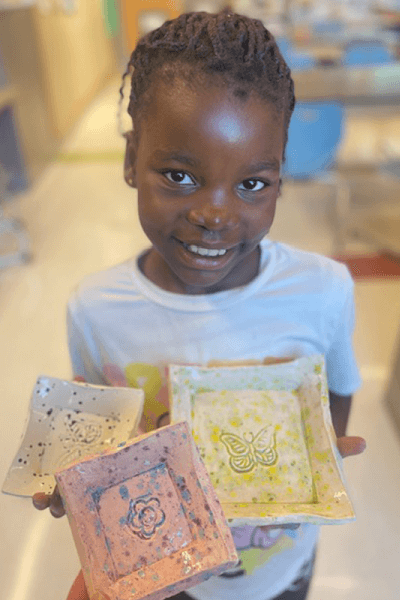 Lewiston Public Schools student happily showing off art work.