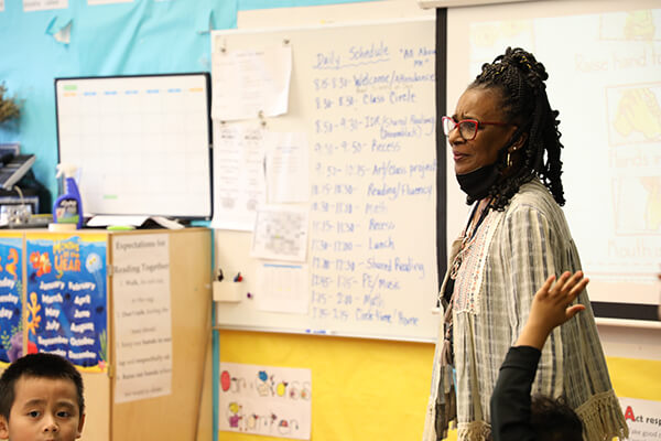 A Seattle Public Schools teacher standing in front of a classroom listening to a student response.