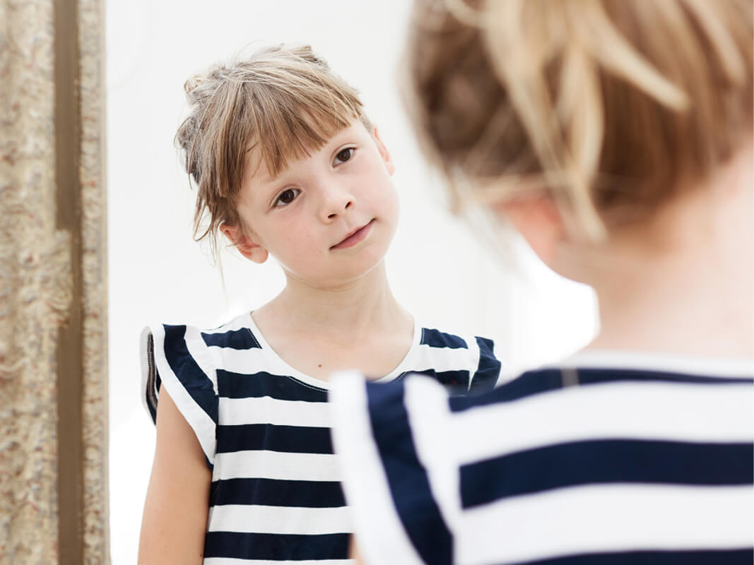 A phenomena-based science lesson where a student stands in front of a mirror to see if she will see more of herself when she moves backwards, or if she will see the same amount of herself.