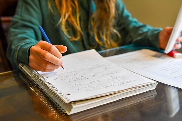 Photo of an individual high school student working quietly on a math problem at their desk.