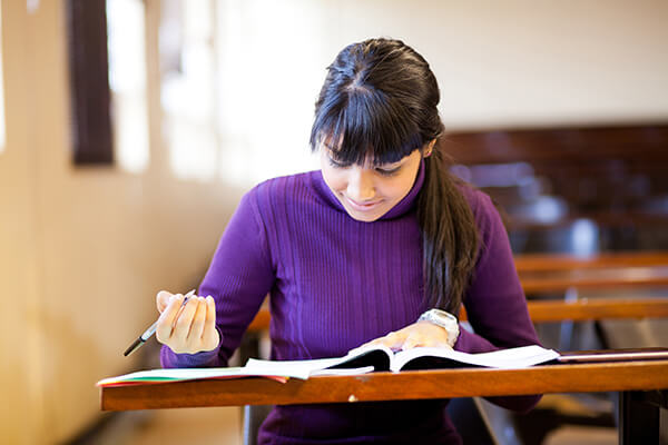 Middle school student sitting at her desk working on a writing assignment.